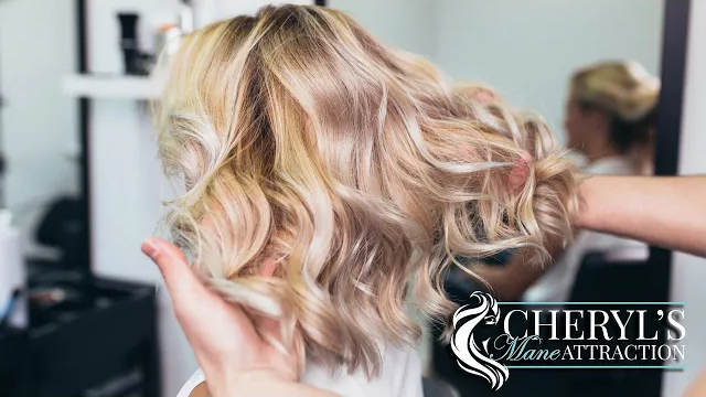 A blonde women getting hair styled and Cheryl's Mane Attraction logo.